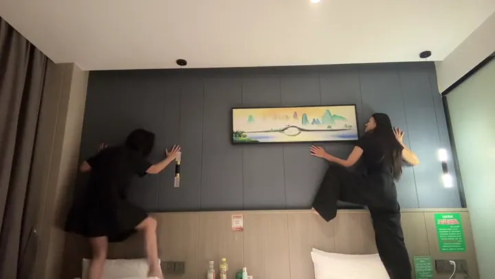 Two men pressed against hotel wall eavesdropping on couple next door