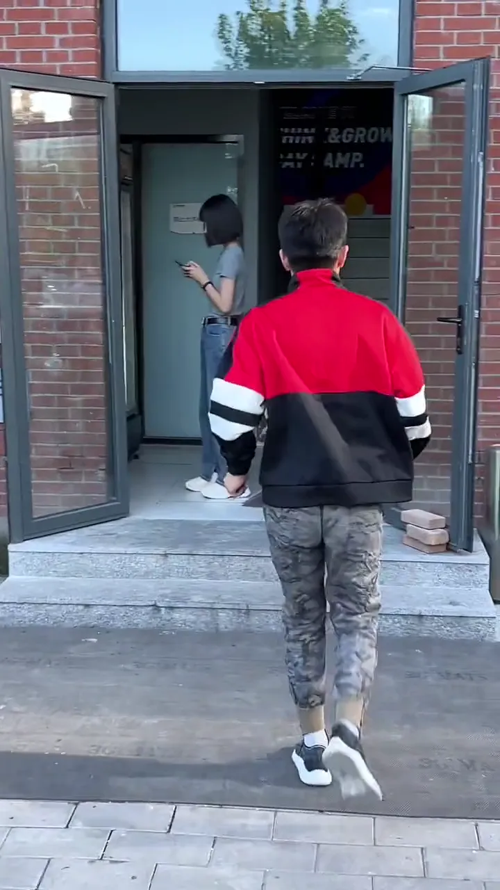 Guy awkwardly handing a blade of grass to a stranger after his friend yells embarrassing question